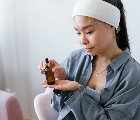 calm asian woman with bottle of oil