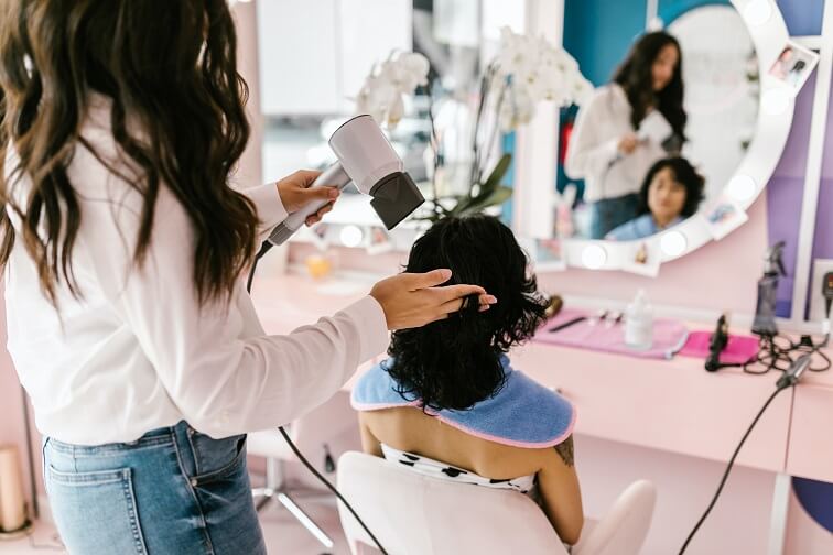 A woman getting her hair blow dried by a hairstylist
