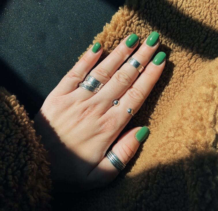 person wearing silver ring with green manicure