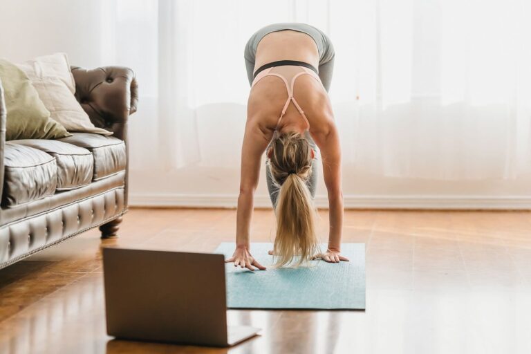Woman doing yoga with laptop on floor in front of her