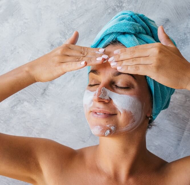 a beautiful woman applying facial cream