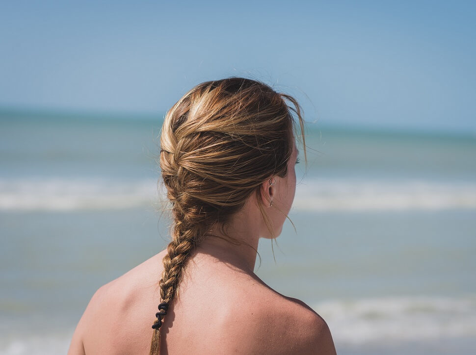 A woman on the beach with a french braid in her hair