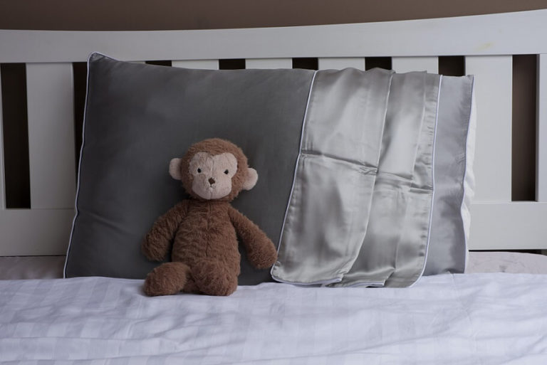 A monkey stuffed animal leaned against silk-covered pillows.