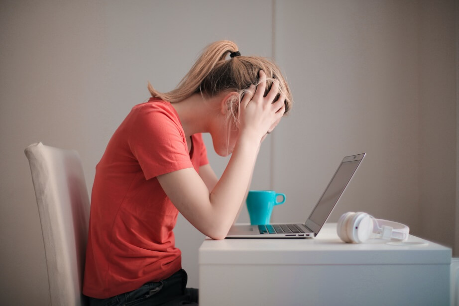 Woman leaning over her laptop, stressed