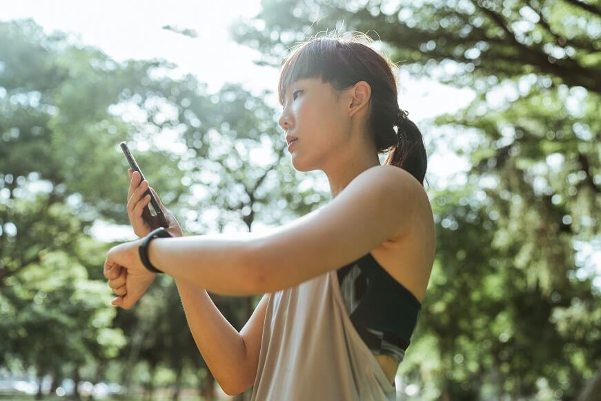 Femme utilisant un téléphone portable et une montre pour suivre l'entraînement