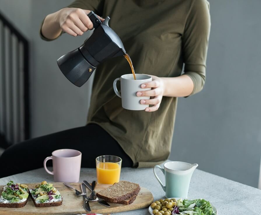 Woman pouring coffee and having breakfast