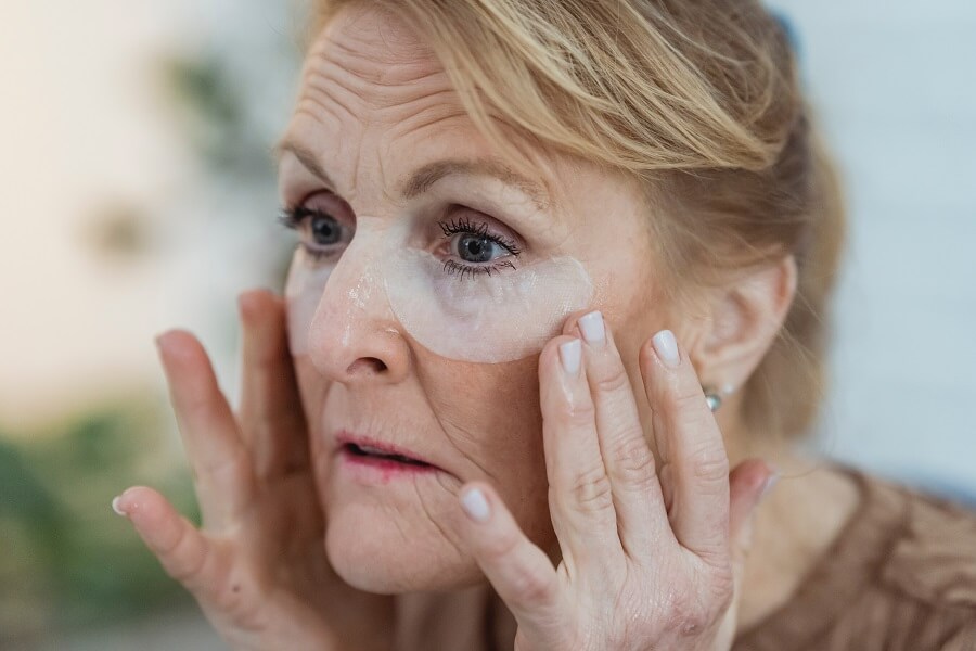 Aging woman using undereye strips
