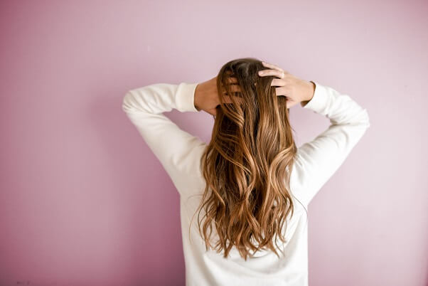Woman with her back to the camera and running her fingers through her hair