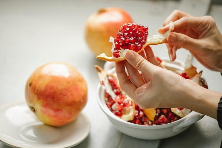 woman peeling pomegranate seeds on kitchen
